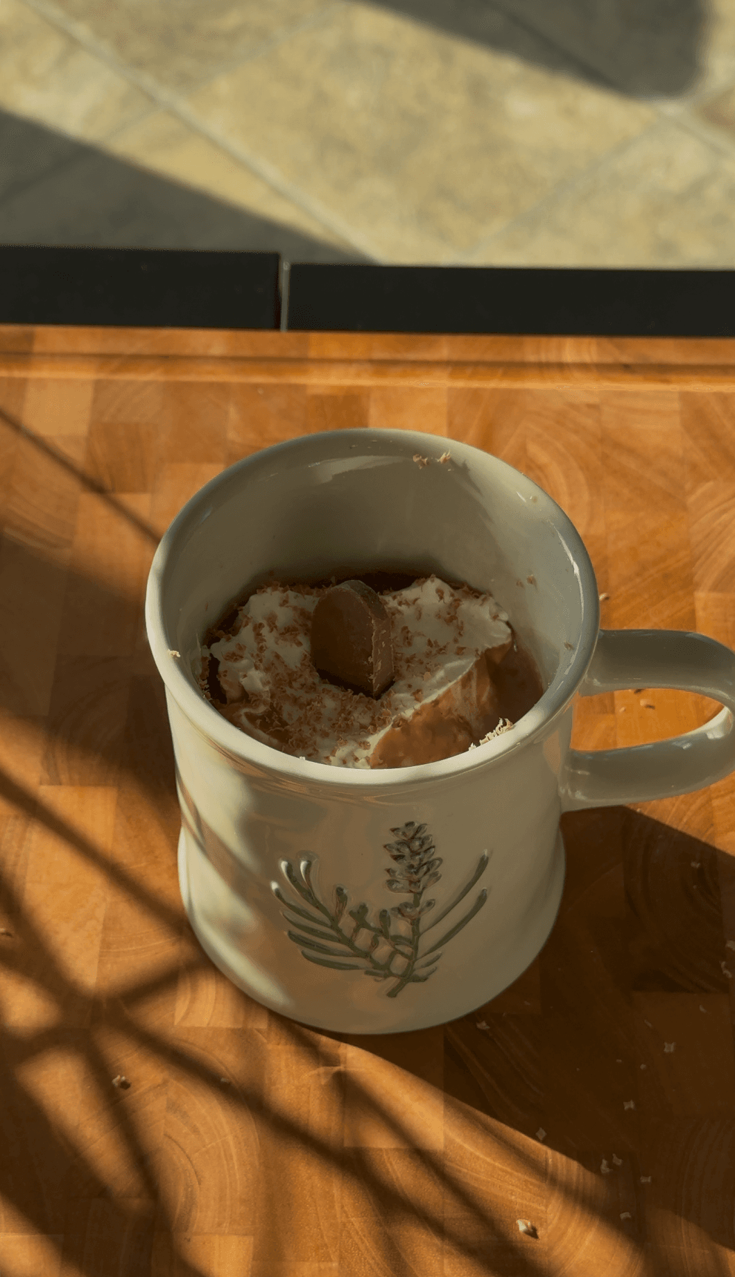 Steam rising off a mug of hot chocolate in warm window light
